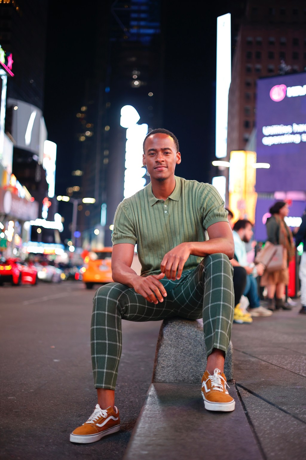 Stephon Dingle seated in Times Square at night.