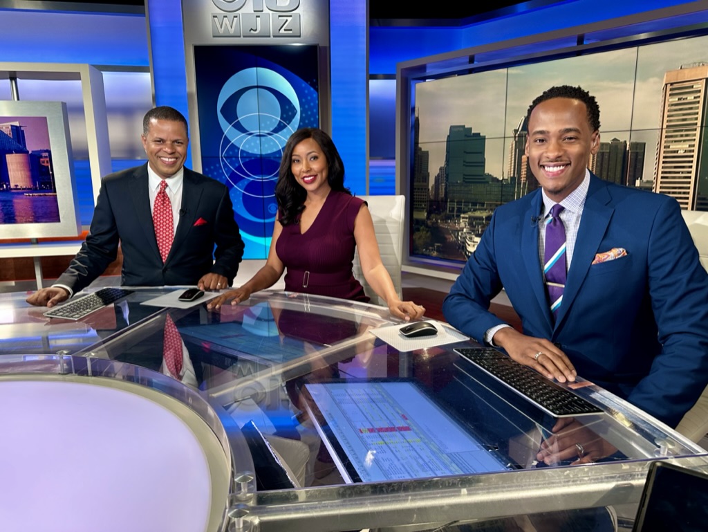 Stephon Dingle smiles alongside colleagues at the WJZ anchor desk.