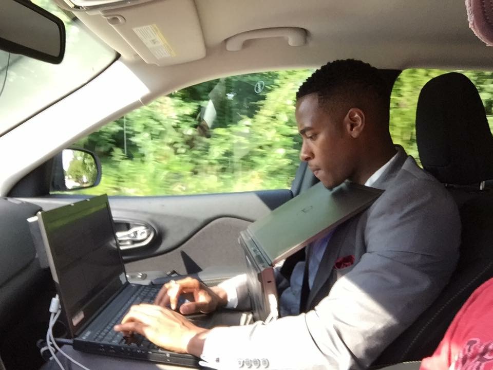 Stephon Dingle writing from the road with a laptop and reporting files open