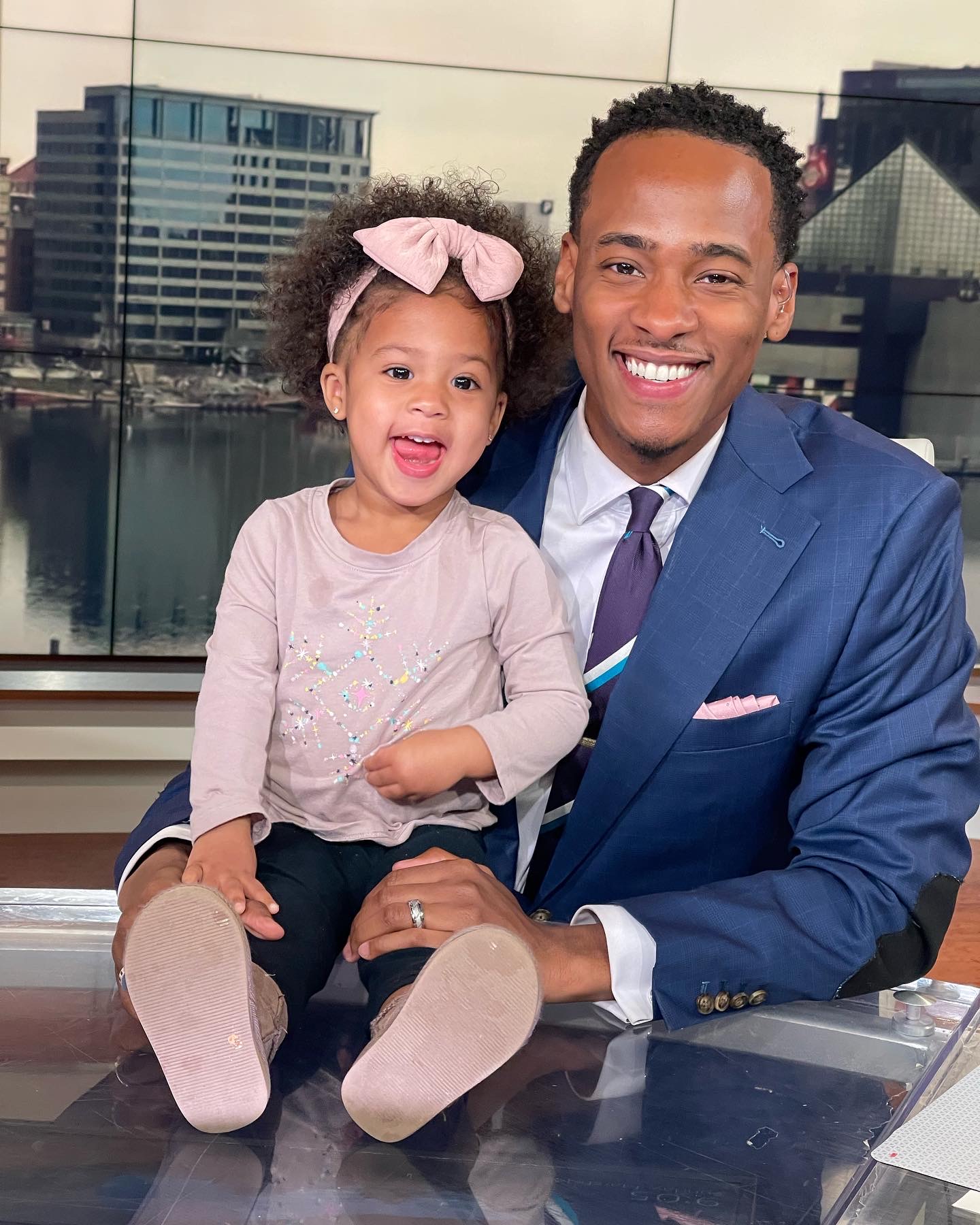 Stephon Dingle seated with his daughter Devyn at a television news anchor desk in Baltimore.