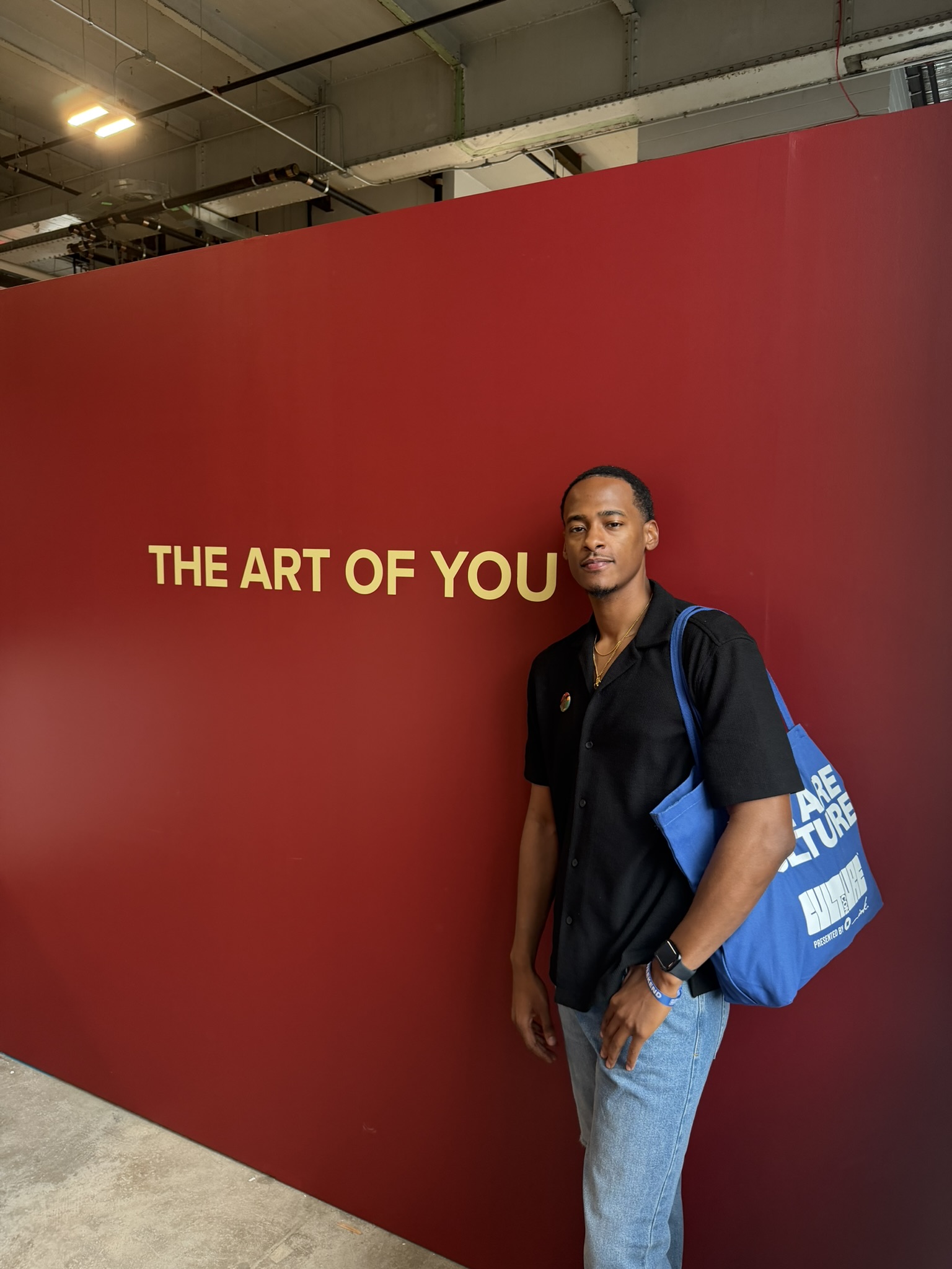 Stephon Dingle standing before a red wall reading The Art of You at CultureCon in New York.